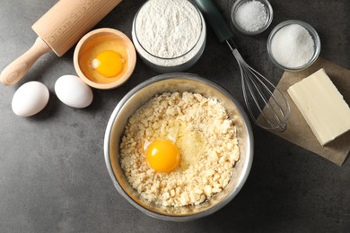 Making shortcrust pastry. Different ingredients for dough, rolling pin and whisk on grey table, flat lay