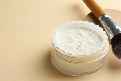 Photo of Rice loose face powder and makeup brush on beige background, closeup. Space for text