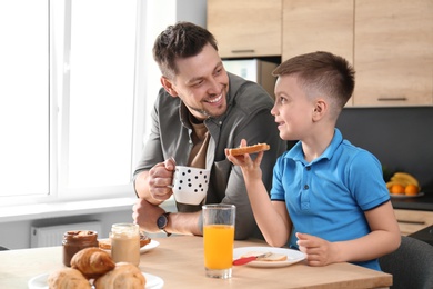 Photo of Dad and son having breakfast together in kitchen