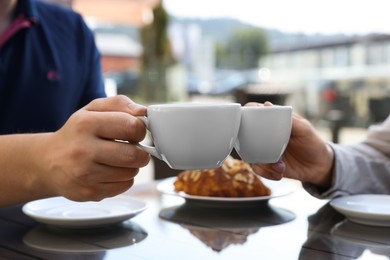 Photo of Man and woman drinking coffee at wooden table in outdoor cafe, closeup