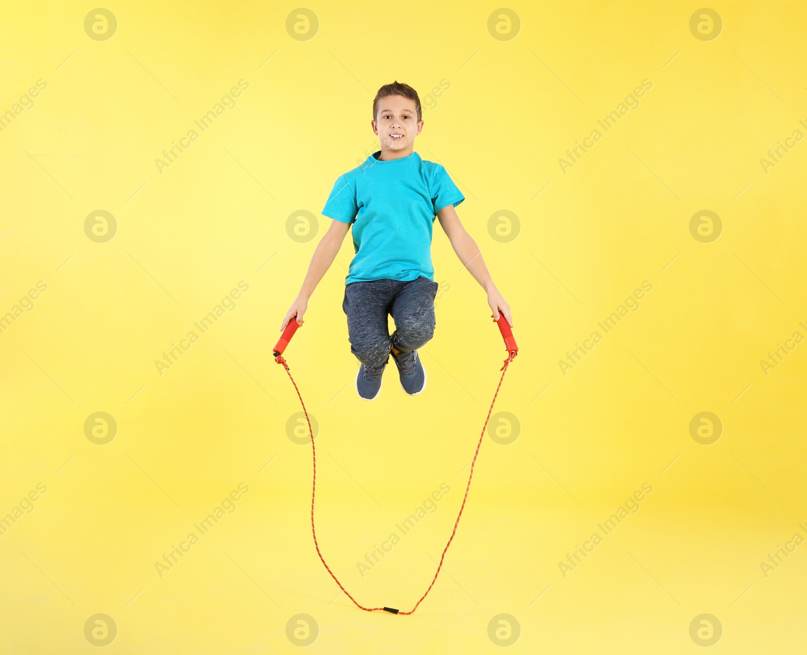 Photo of Full length portrait of boy jumping rope on color background