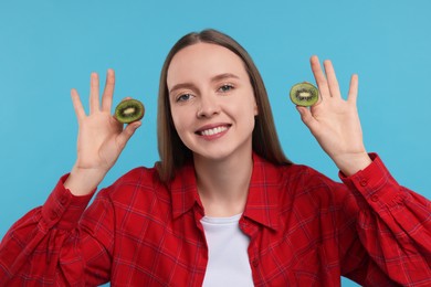 Photo of Young woman holding halves of kiwi on light blue background