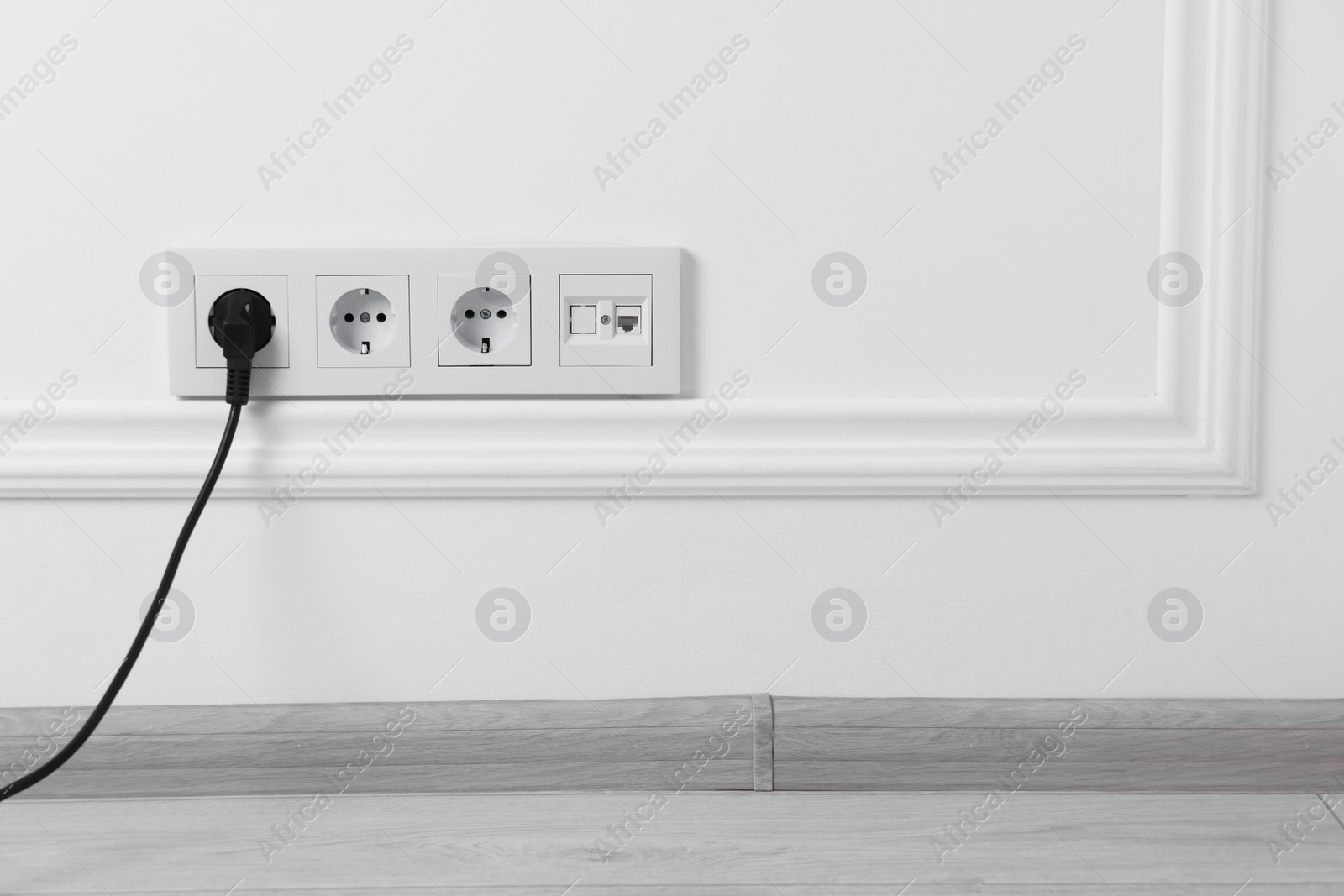 Photo of Power sockets and electric plug on white wall, space for text