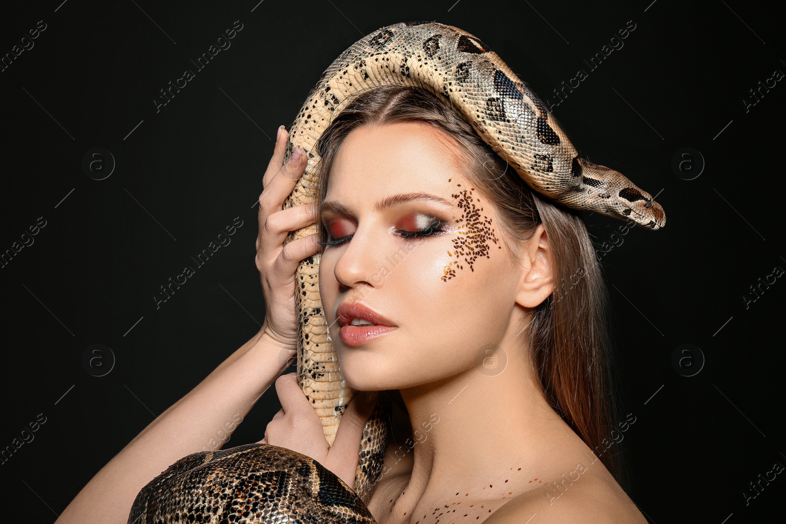 Photo of Beautiful woman with boa constrictor on black background