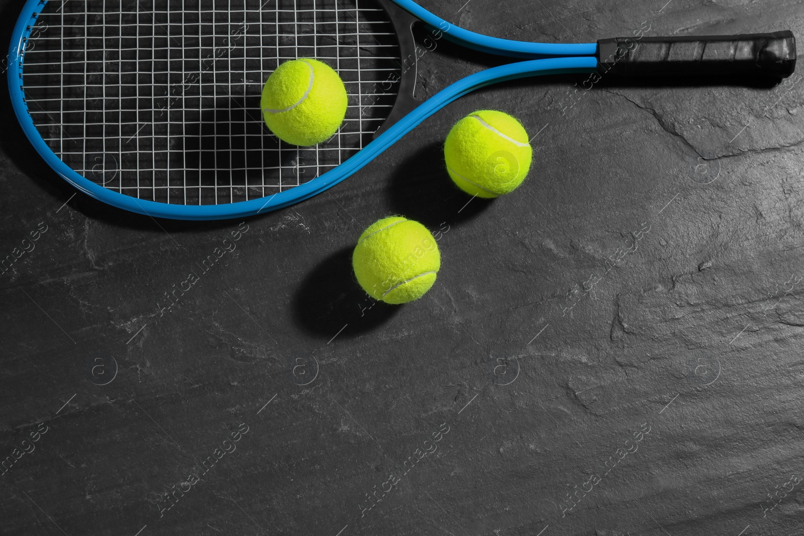 Photo of Tennis racket and balls on black table, flat lay. Sports equipment