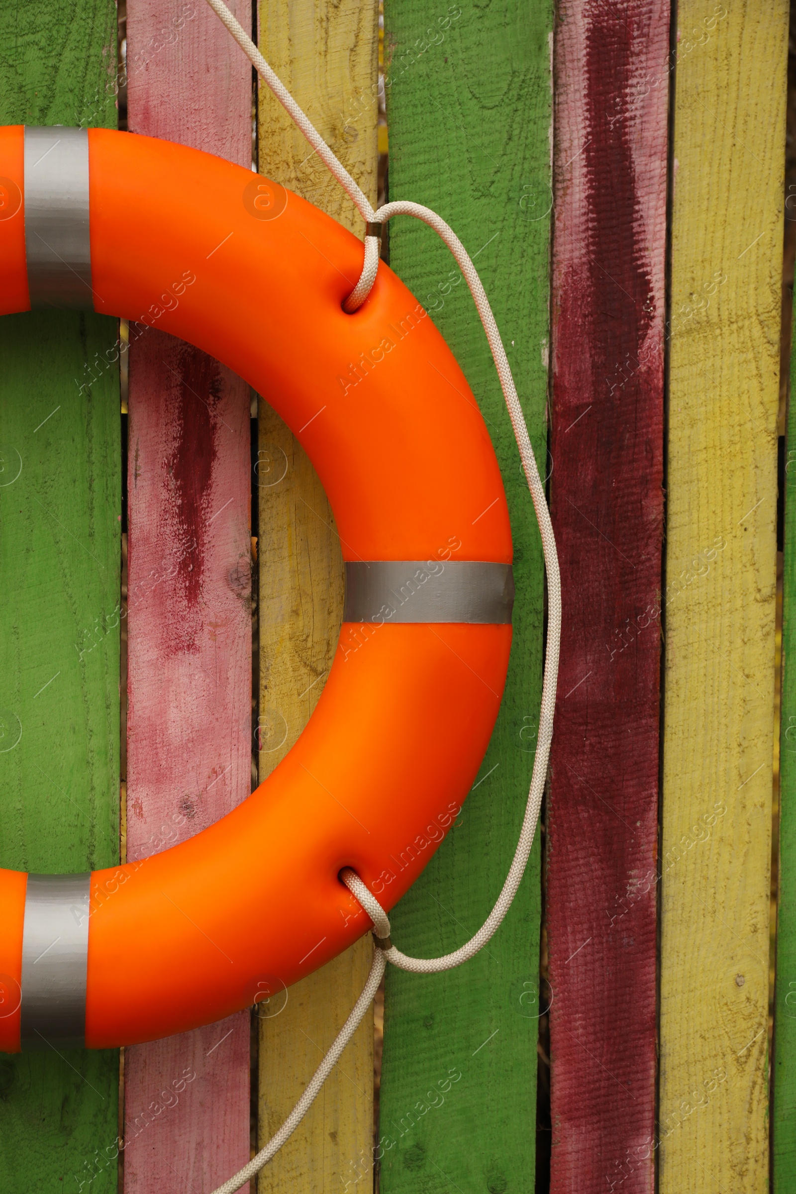 Photo of Orange lifebuoy hanging on color wooden fence. Rescue equipment