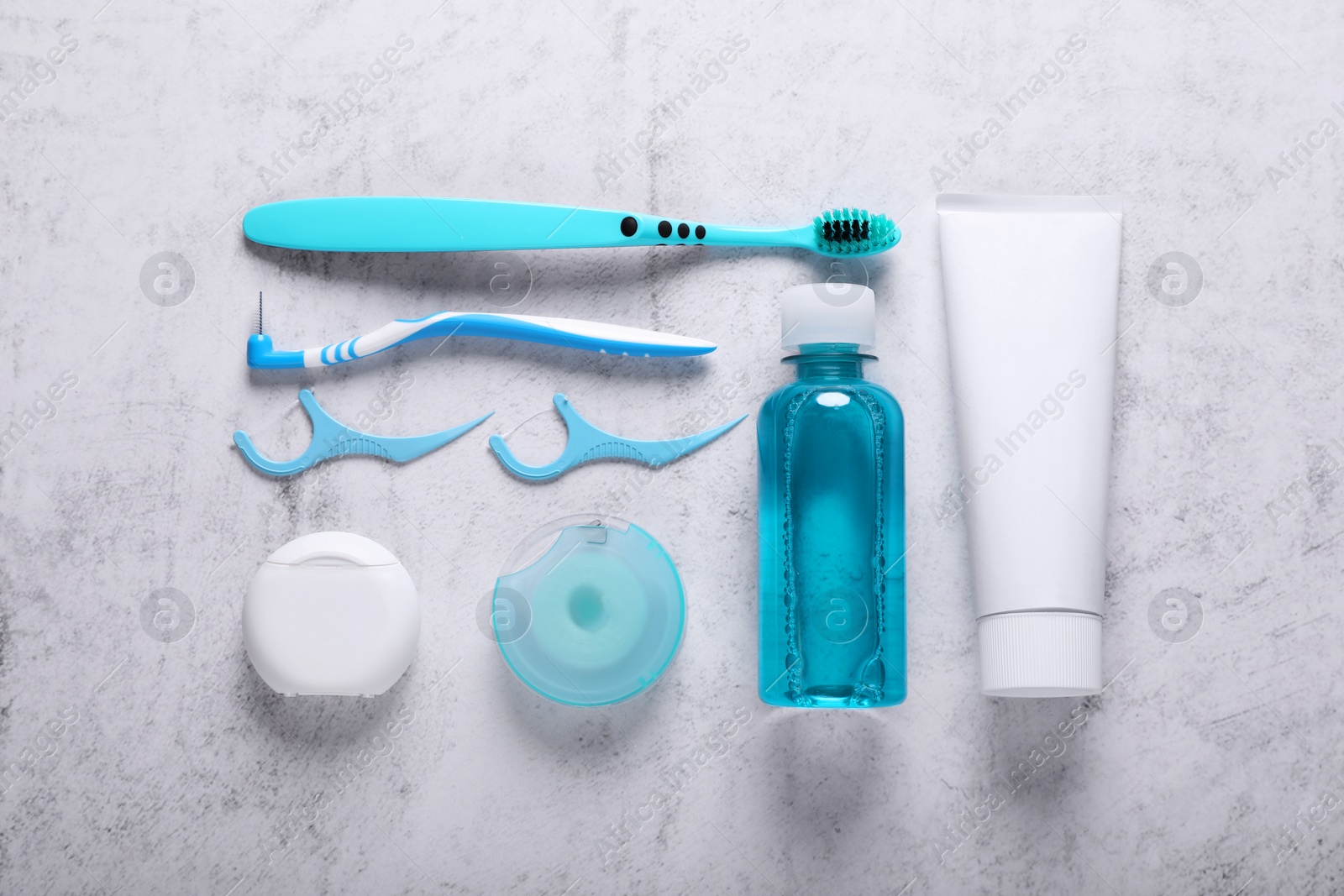 Photo of Flat lay composition with dental floss and different teeth care products on light grey textured table