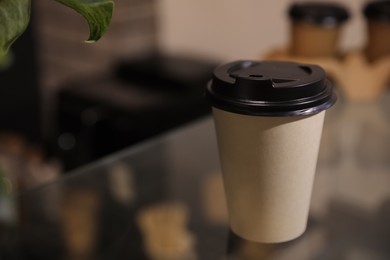 Photo of Takeaway coffee cup with plastic lid on glass table in cafe. Space for text