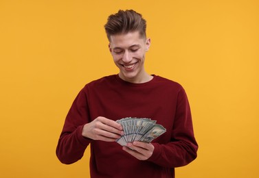 Photo of Happy man with dollar banknotes on yellow background