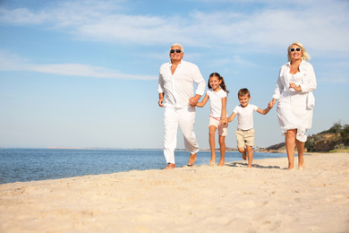 Photo of Cute little children with grandparents spending time together on sea beach