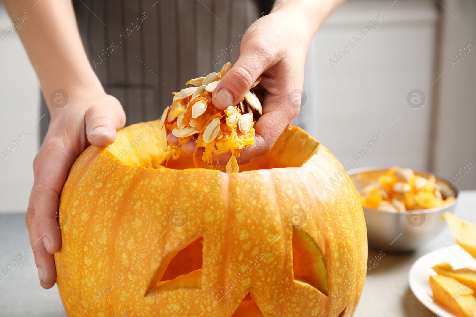 Photo of Woman making pumpkin head Jack lantern for Halloween at light table indoors, closeup