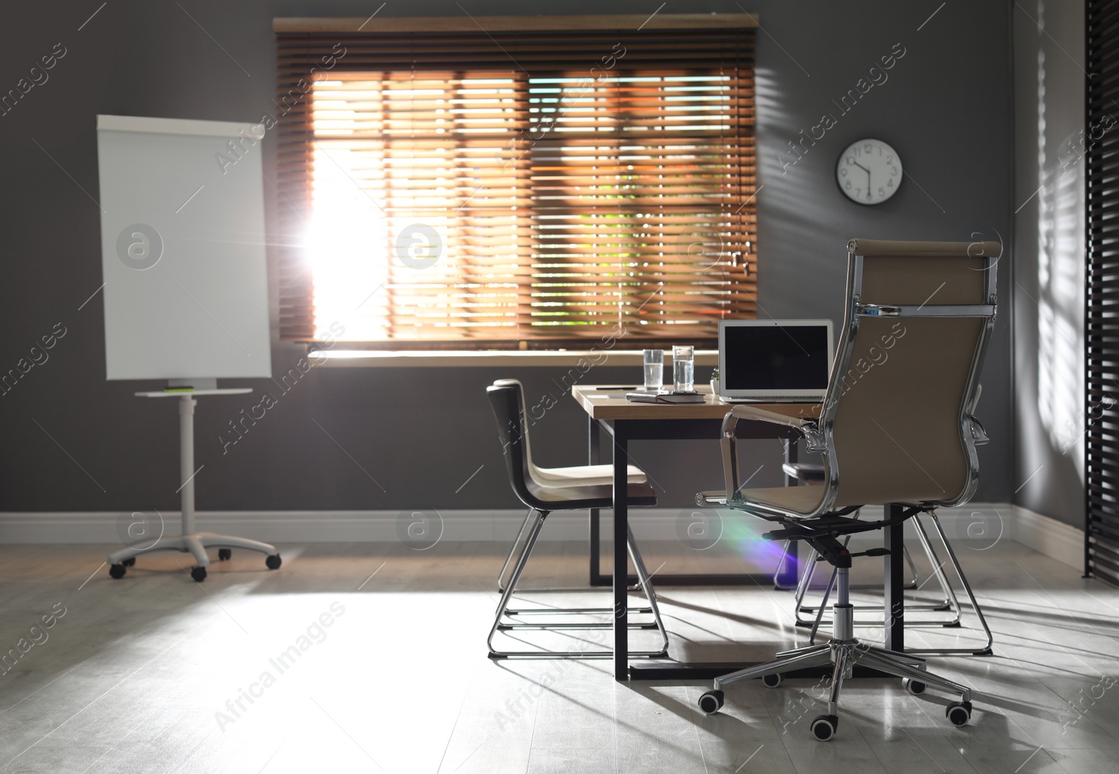 Photo of Stylish office interior with wooden table and flipchart