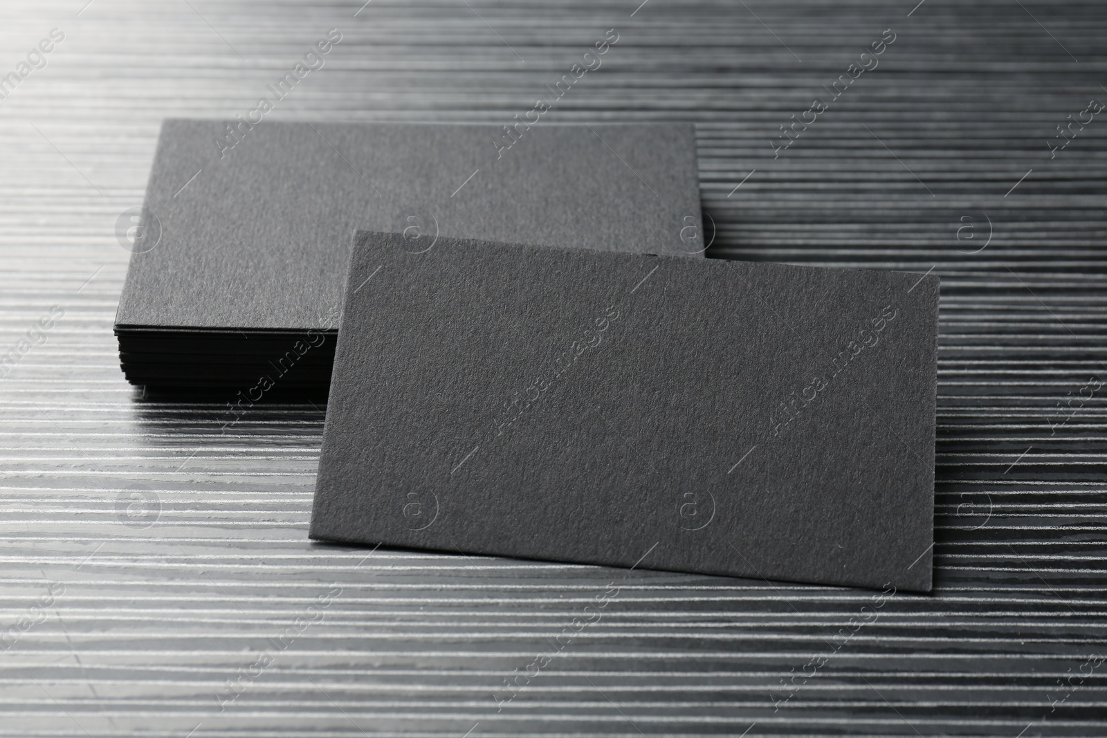 Photo of Blank black business cards on wooden table, closeup. Mockup for design