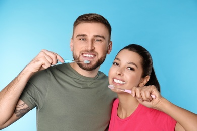 Photo of Young couple with toothbrushes on color background. Teeth care