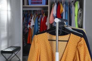 Rack with stylish women's clothes in dressing room, closeup