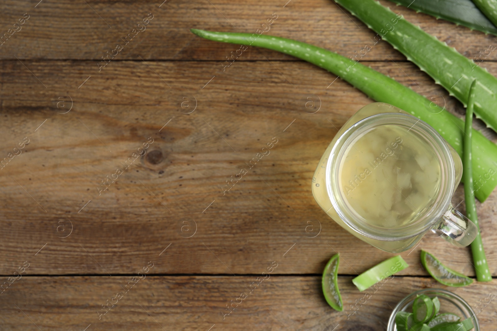 Photo of Fresh aloe drink in mason jar and leaves on wooden table, flat lay. Space for text