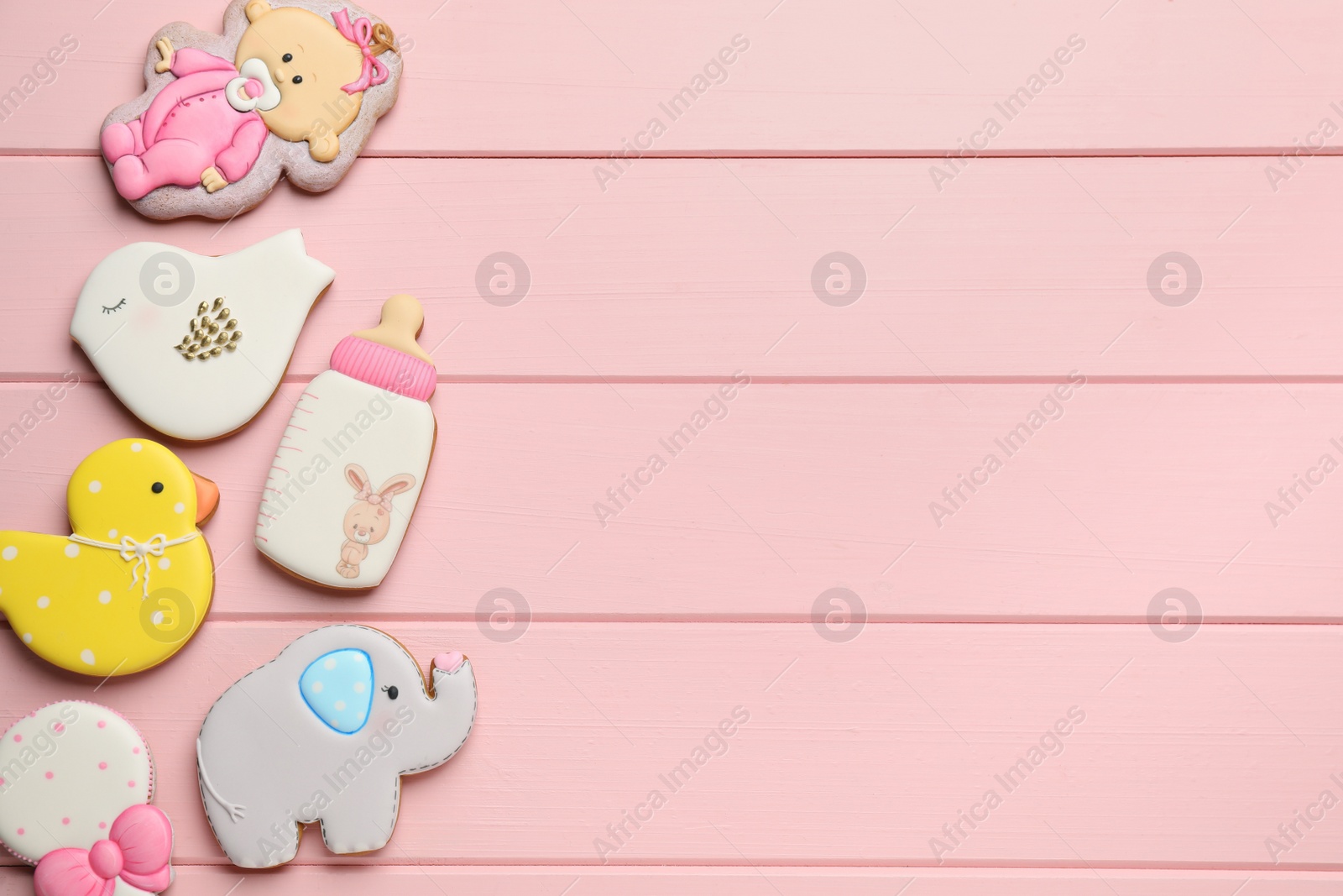 Photo of Cute tasty cookies of different shapes and space for text on pink wooden table, flat lay. Baby shower party