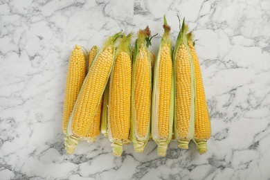 Photo of Tasty sweet corn cobs on marble table, top view