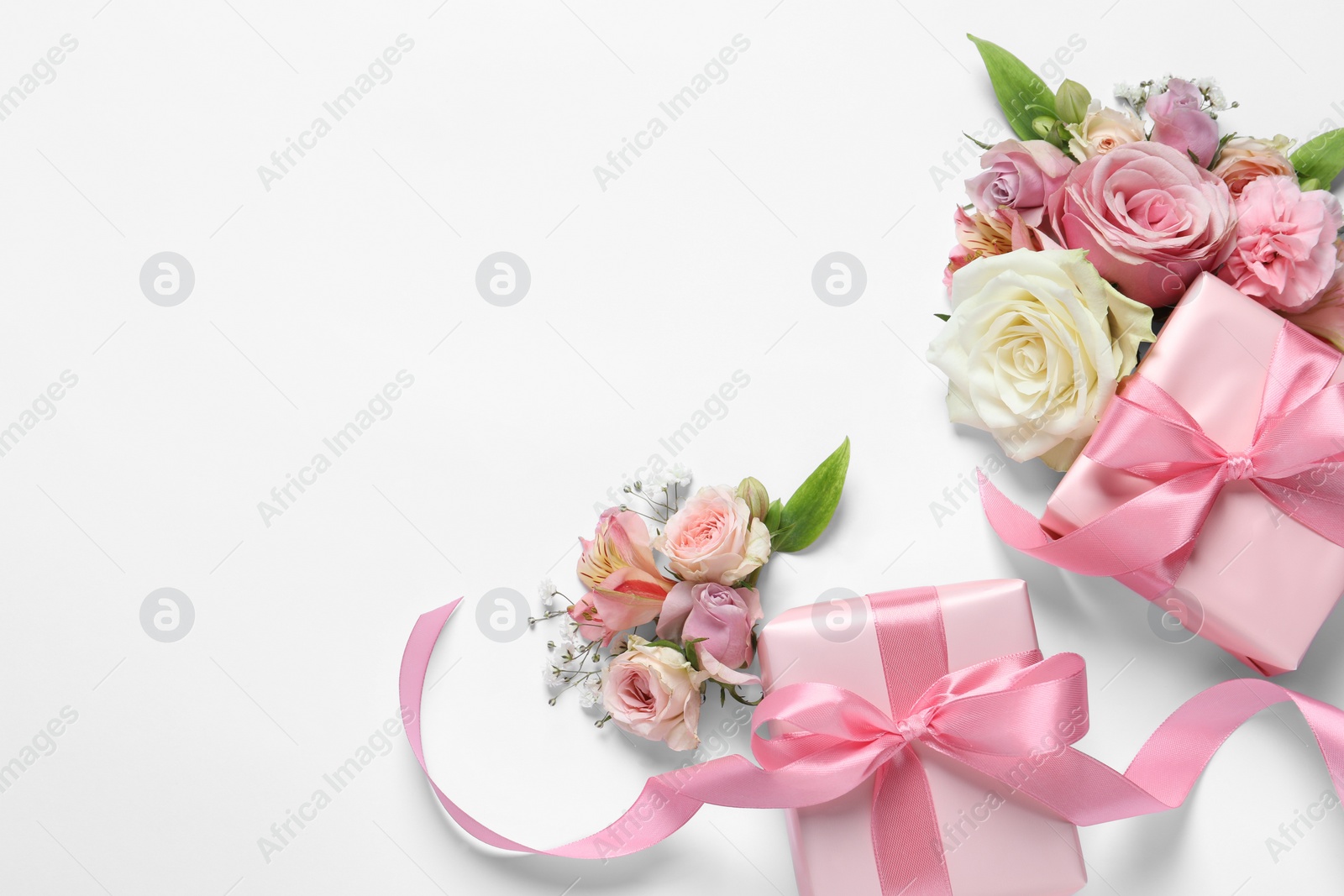 Photo of Gift boxes and beautiful flowers on white background, flat lay. Space for text