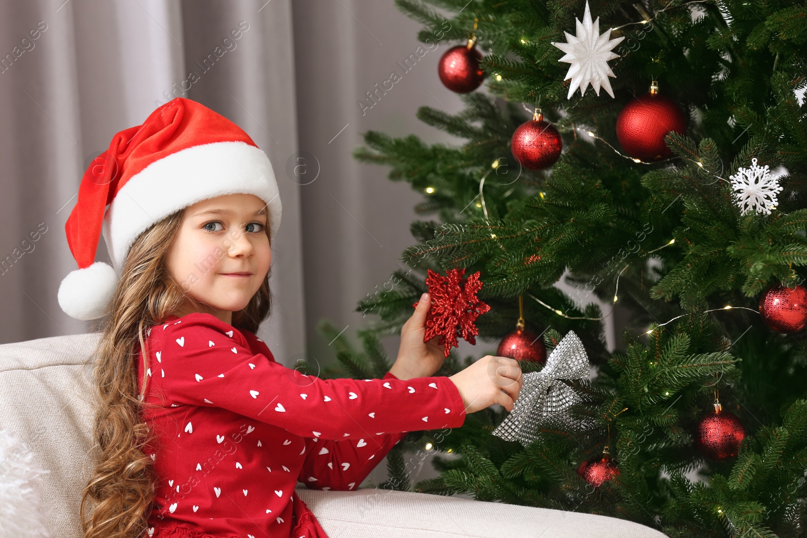 Photo of Cute girl decorating Christmas tree at home