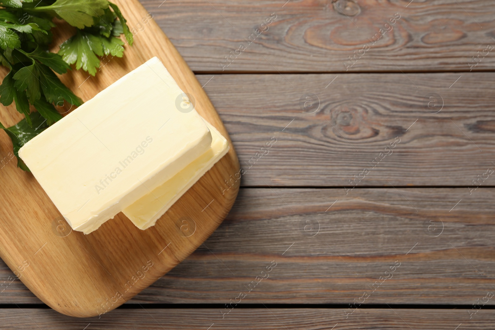 Photo of Tasty butter and parsley on wooden table, top view. Space for text