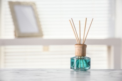 Photo of Aromatic reed air freshener on white table at home, space for text