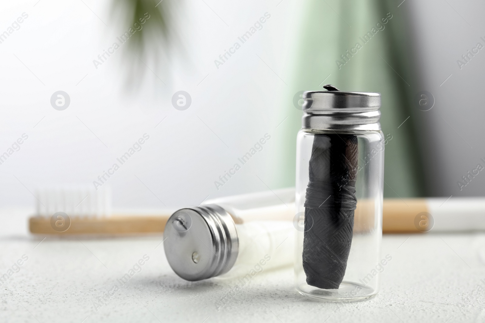 Photo of Biodegradable dental flosses in glass jars on white table, closeup. Space for text