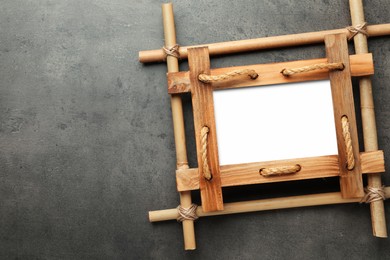 Photo of Empty bamboo frame on grey table, top view. Space for text