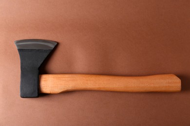 Photo of Ax with wooden handle on brown background, top view