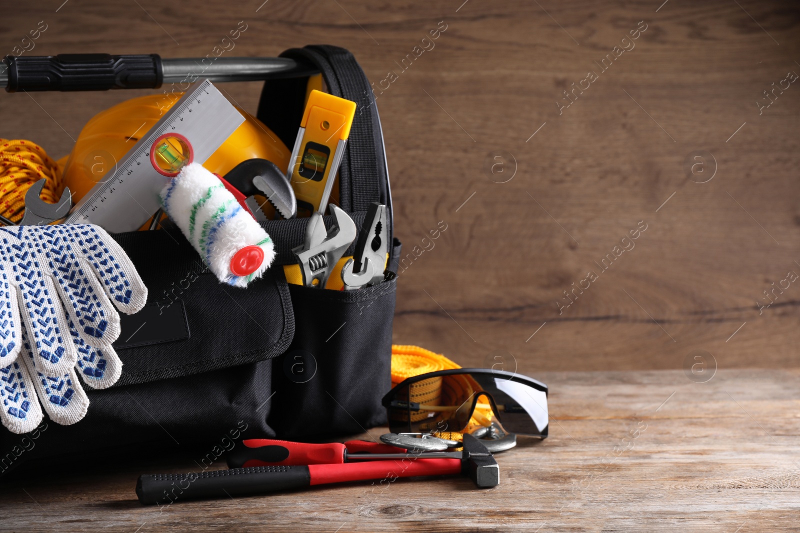 Photo of Black bag with construction tools on wooden table. Space for text