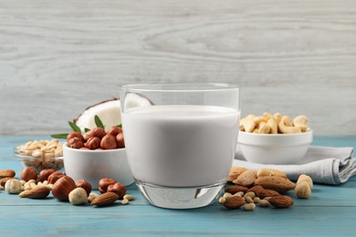 Vegan milk and different nuts on light blue wooden table