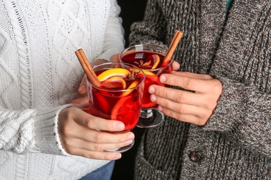 Photo of Man and woman holding glasses with hot mulled wine, closeup. Romantic holiday moment