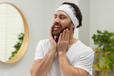 Photo of Washing face. Man with headband in bathroom