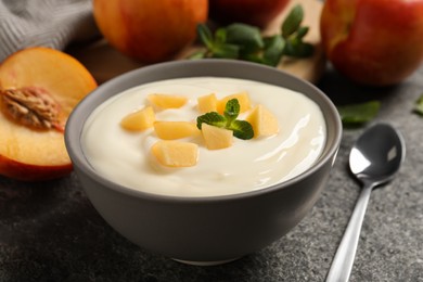 Photo of Delicious yogurt with fresh peach and mint on grey table, closeup