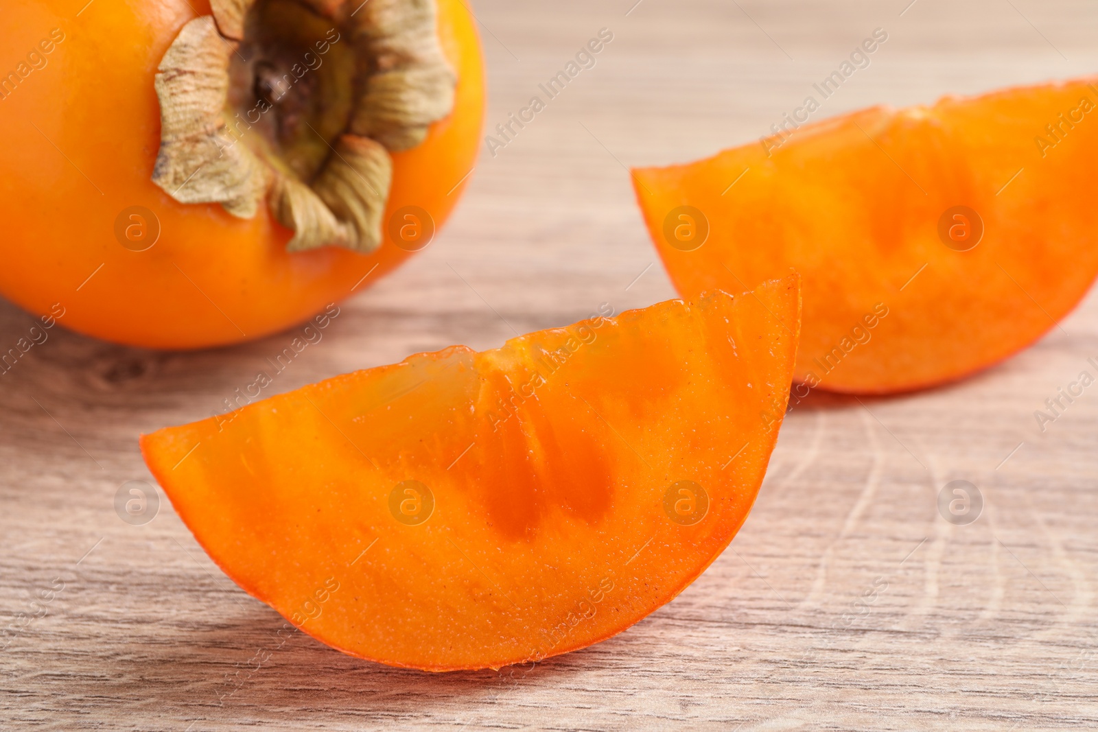 Photo of Delicious ripe persimmons on light wooden table, closeup