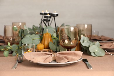 Autumn table setting with eucalyptus branches and pumpkins indoors