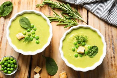 Photo of Fresh vegetable detox soup made of green peas and spinach with croutons served on table