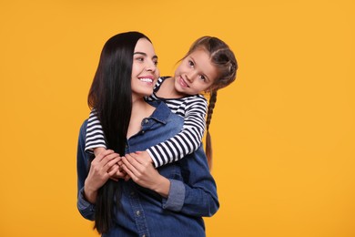 Photo of Happy woman with her cute daughter on yellow background. Mother's day celebration