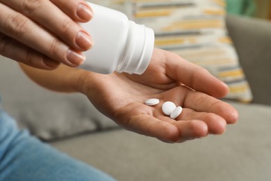 Photo of Woman pouring pills from bottle indoors, closeup. Menopause concept