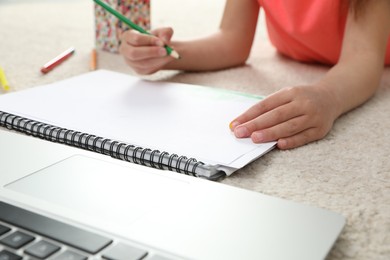 Little girl drawing on paper with pencil at online lesson indoors, closeup. Distance learning