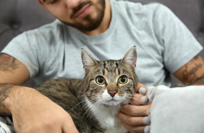 Photo of Man with cat on bed at home, closeup. Friendly pet