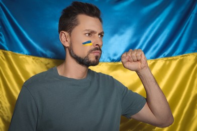 Photo of Angry man with face paint near Ukrainian flag