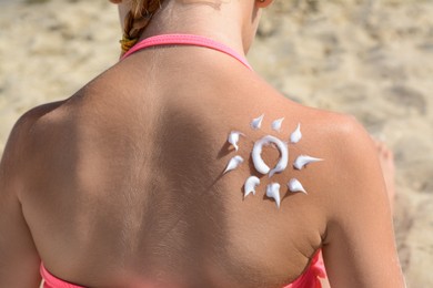 Photo of Little girl with sun protection cream on back outdoors, closeup
