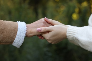 Photo of Trust and support. Women joining hands outdoors, closeup
