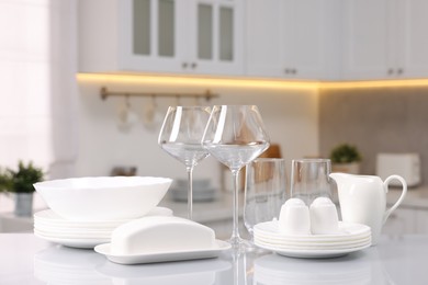 Photo of Set of clean dishware and glasses on table in kitchen