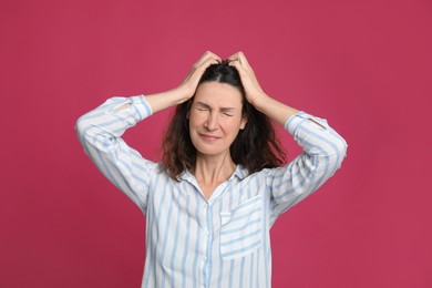 Photo of Mature woman suffering from headache on pink background
