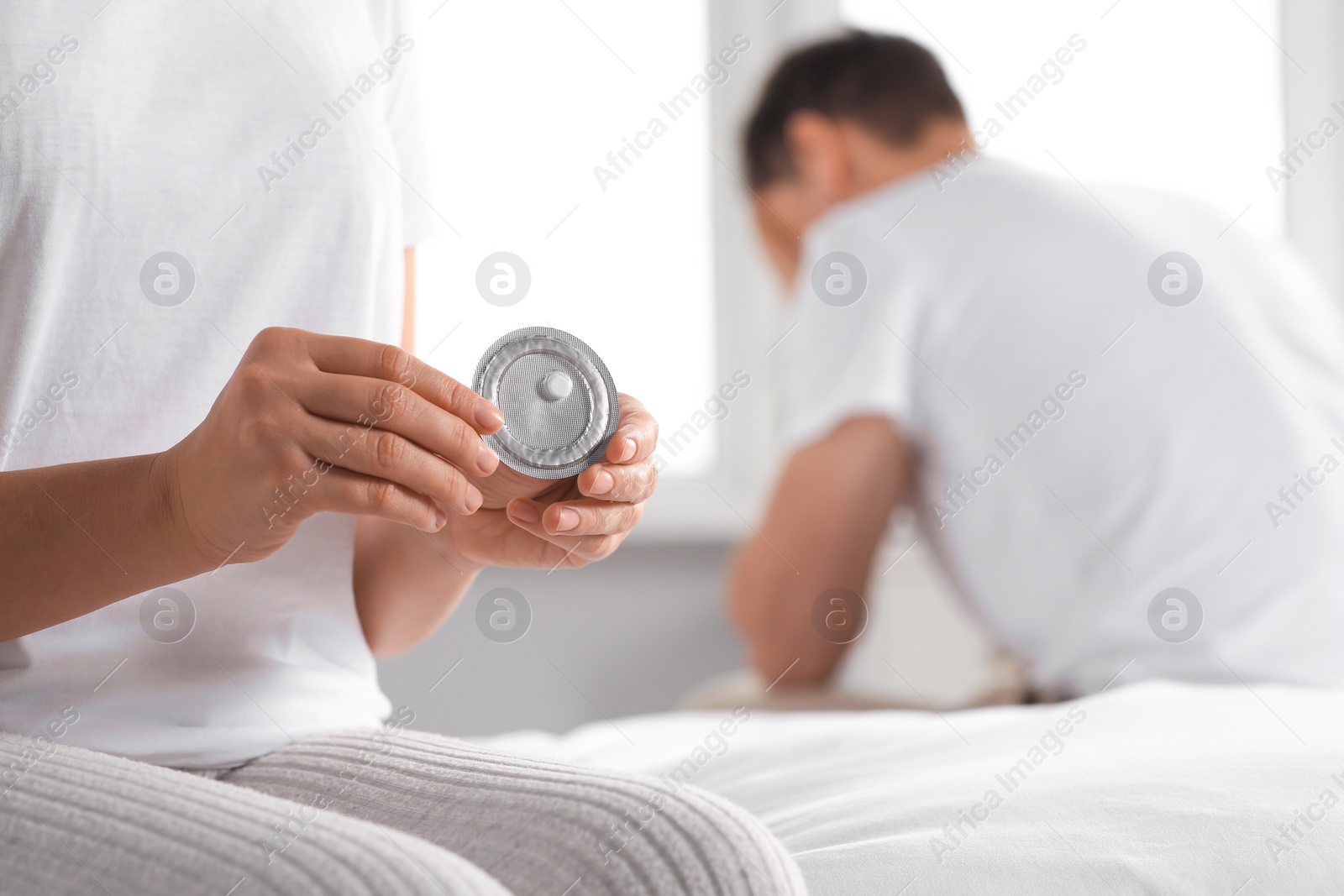 Photo of Couple in bedroom. Woman with blister of emergency contraception pill, closeup