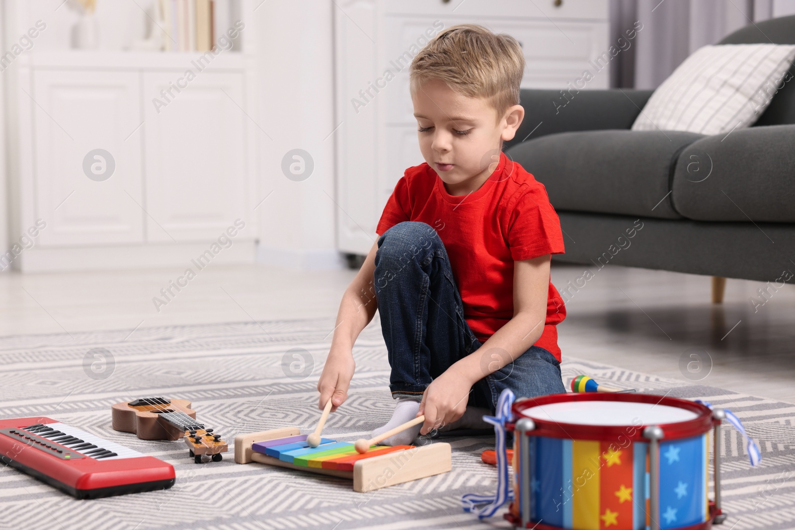 Photo of Little boy playing toy xylophone at home