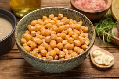 Photo of Delicious chickpeas on wooden table, closeup. Hummus ingredient