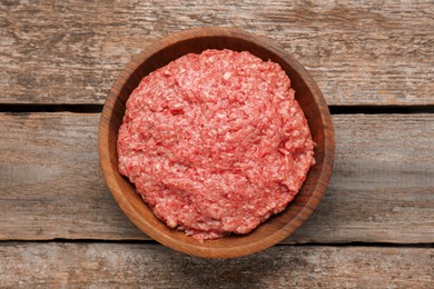 Bowl with raw fresh minced meat on wooden table, top view